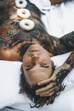 Genç yakışıklı adam açık havada bahçede açık havada yatakta kahvaltı dövme