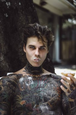 Genç yakışıklı adam açık havada bahçede açık havada yatakta kahvaltı dövme