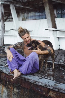 Uzun sarı saçlı ve köpekle oynamayı dövmeler yakışıklı yetişkin adam