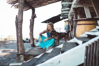 Uzun sarı saçlı ve köpekle oynamayı dövmeler yakışıklı yetişkin adam