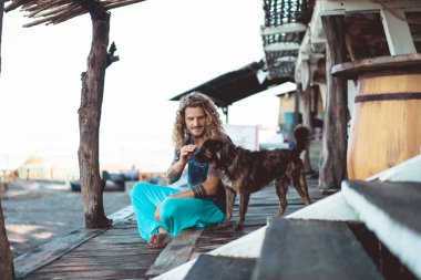 Uzun sarı saçlı ve köpekle oynamayı dövmeler yakışıklı yetişkin adam