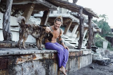 Uzun sarı saçlı ve köpekle oynamayı dövmeler yakışıklı yetişkin adam