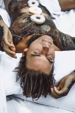 Genç yakışıklı adam açık havada bahçede açık havada yatakta kahvaltı dövme