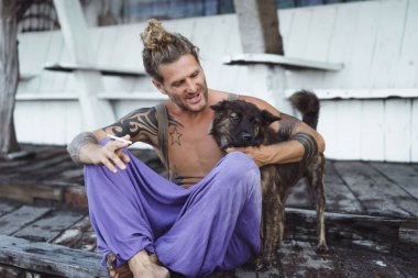 Uzun sarı saçlı ve köpekle oynamayı dövmeler yakışıklı yetişkin adam