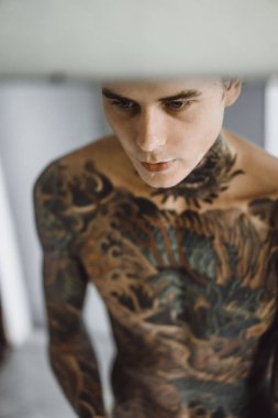 bir ayna, onun elinde bir tıraş jilet önünde genç bir yakışıklı dövmeli adam sabah tıraş.