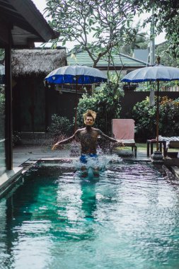 Açık Yüzme havuzunda dinlenme dövmeler genç yakışıklı adam. Dövmeli bir adam havuzda eğleniyor. Bali, Endonezya