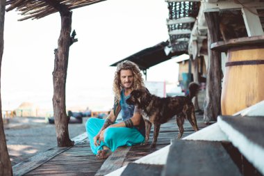 Uzun sarı saçlı ve köpekle oynamayı dövmeler yakışıklı yetişkin adam