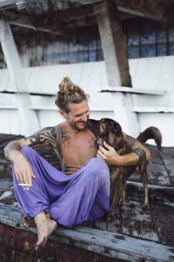 Uzun sarı saçlı ve köpekle oynamayı dövmeler yakışıklı yetişkin adam