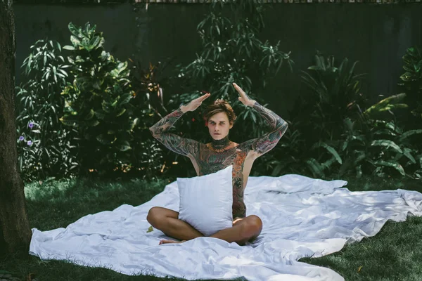 一个年轻英俊的纹身男子在早上在床上扔枕头 床在庭院里 — 图库照片