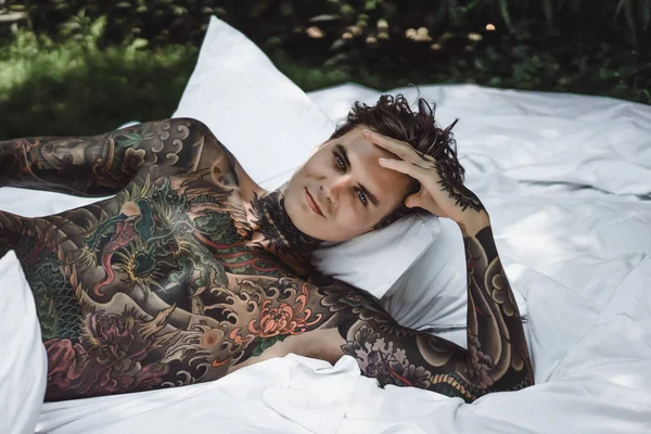 Yakışıklı Genç Bir Dövmeli Adam Sabah Yatakta Yastık Fırlatır Bahçe — Stok fotoğraf