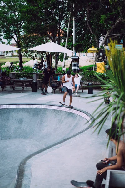 Bir havuzda pateni bir şık genç adam bir skatepark, bir kaykay üzerinde beyaz bir T-shirt ve şapka paten.
