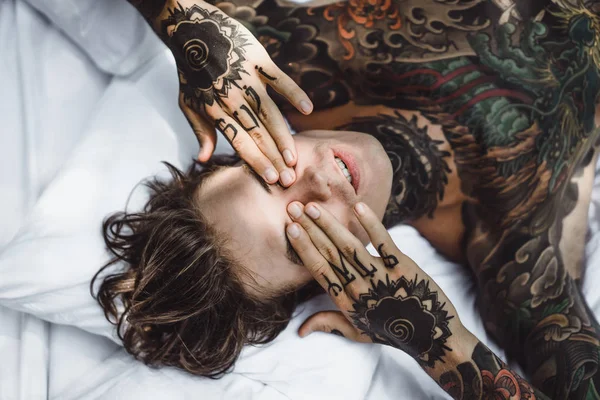 Beau Jeune Homme Tatoué Relaxant Sur Lit Blanc — Photo