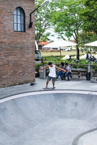 Bir havuzda pateni bir şık genç adam bir skatepark, bir kaykay üzerinde beyaz bir T-shirt ve şapka paten.