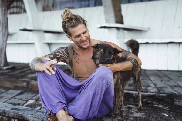 Uzun sarı saçlı ve köpekle oynamayı dövmeler yakışıklı yetişkin adam