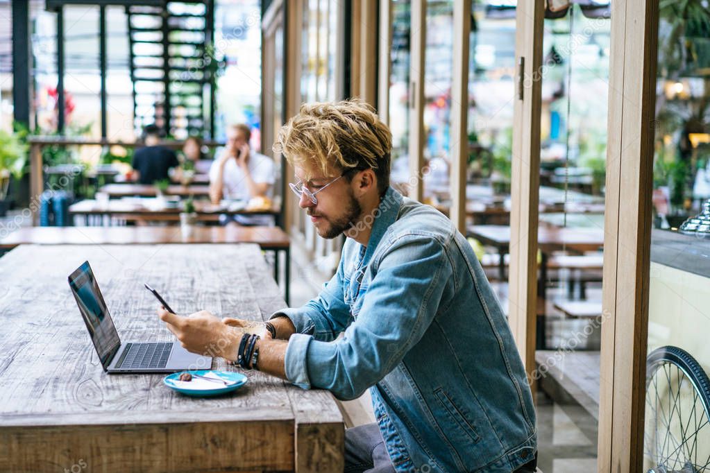 Handsome young man with laptop in outdoor cafe