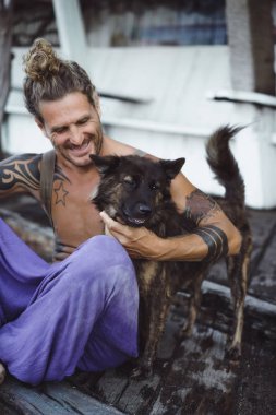 Uzun sarı saçlı ve köpekle oynamayı dövmeler yakışıklı yetişkin adam