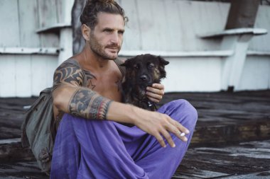 Uzun sarı saçlı ve köpekle oynamayı dövmeler yakışıklı yetişkin adam