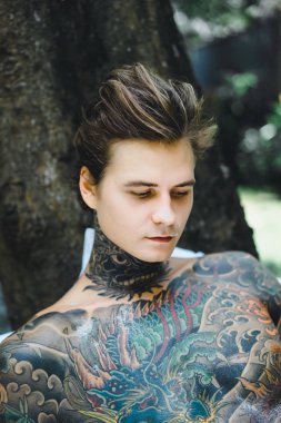 Genç yakışıklı adam açık havada bahçede açık havada yatakta kahvaltı dövme