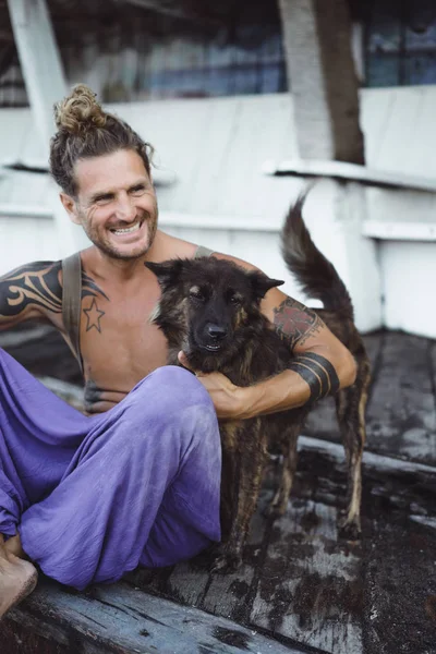 Красивий Дорослий Чоловік Довгим Світлим Волоссям Татуюваннями Грають Собакою — стокове фото