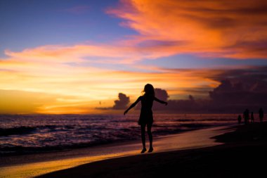 Kız batan güneşin fonunda atlıyor.