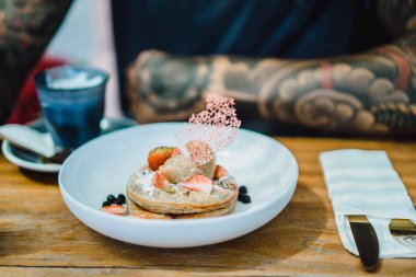 Genç adam yeme krep dövme. Eller, smartphone ve gıda. 