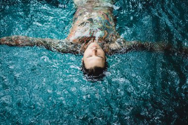 dövmeli adam yağmur havuzunda. yakın çekim, portre, açık havada