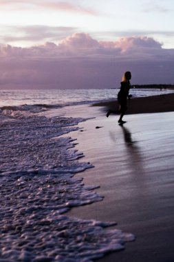 Kız batan güneşin fonunda atlıyor.