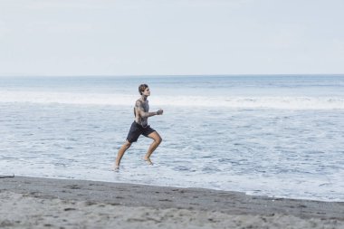okyanus kıyısında bir erkek spor, jimnastik, deniz kıyısı çalışan yapıyor devreye girer. sahilde spor kavramı.