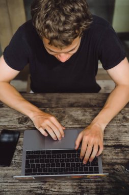 bir dizüstü bilgisayar üzerinde ahşap bir masa, çalışan bir bilgisayar, smartphone, dizüstü bilgisayar, masaüstü üzerinde bir erkeğin elinde bir kafede çalışan adam.