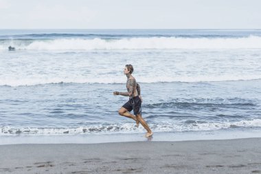 okyanus kıyısında bir erkek spor, jimnastik, deniz kıyısı çalışan yapıyor devreye girer. sahilde spor kavramı.