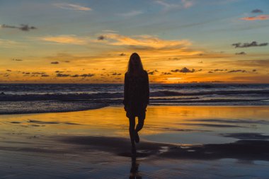 Kız batan güneşin fonunda atlıyor.