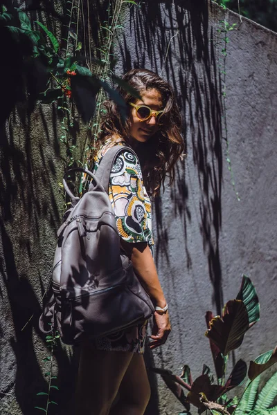 女孩带着背包 戴着太阳镜 在热带花园里 — 图库照片