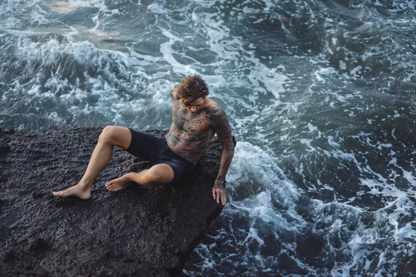 Hombre Tatuado Borde Acantilado Salpicaduras Olas Oceánicas —  Fotos de Stock