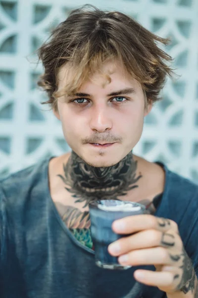 portrait of tattooed man drinks a colorful coffee in a cafe