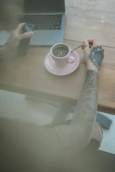 tattooed hands of man. drinking coffee and using laptop concept
