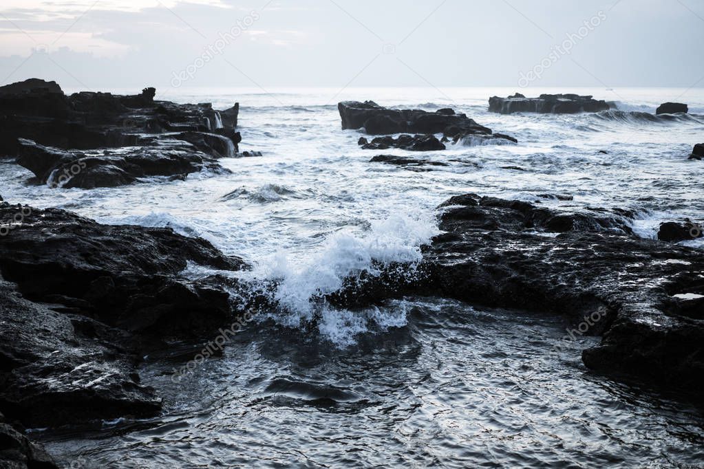 the waves of the ocean are breaking against the rocks. splashing ocean waves at sunset.