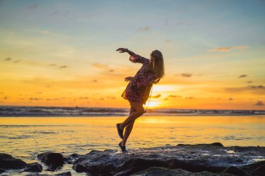 Kız batan güneşin fonunda atlıyor.