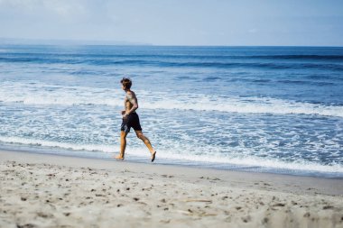 okyanus kıyısında bir erkek spor, jimnastik, deniz kıyısı çalışan yapıyor devreye girer. sahilde spor kavramı.