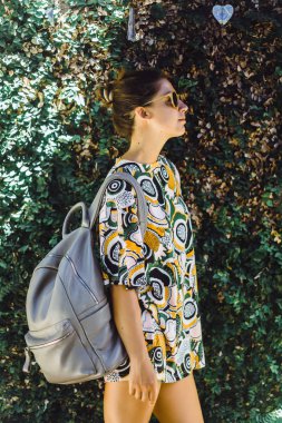 bir sırt çantası, güneş gözlüğü, tropikal bahçede giyen kızla