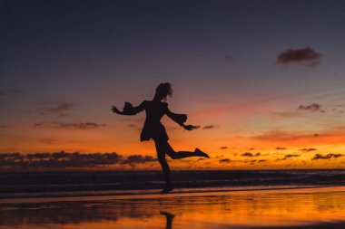 Kız batan güneşin fonunda atlıyor.