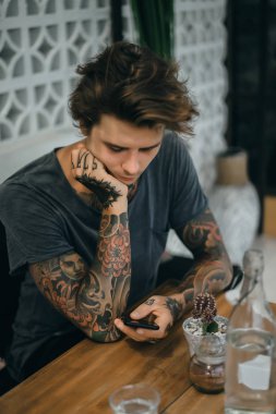 bir sipariş için bekleyen bir smartphone, içecekler kahve, dövmeli bir adam bir kafede kullanır.