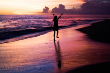 Kız batan güneşin fonunda atlıyor.