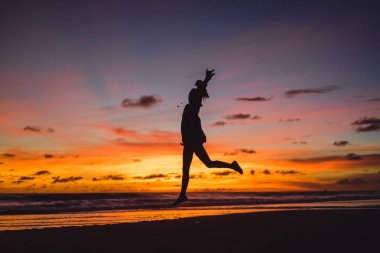Kız batan güneşin fonunda atlıyor.