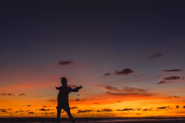Kız batan güneşin fonunda atlıyor.