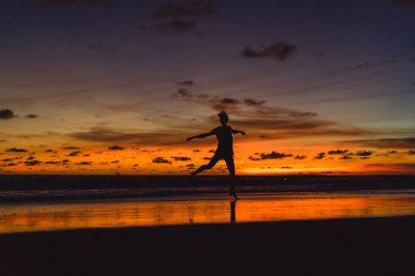 gün batımında okyanusun kıyısında kişi. adam batan güneşin fonunda atlar.