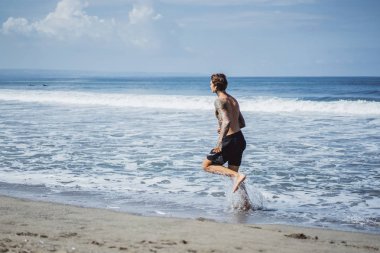 okyanus kıyısında bir erkek spor, jimnastik, deniz kıyısı çalışan yapıyor devreye girer. sahilde spor kavramı.