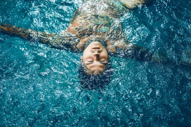 dövmeli adam yağmur havuzunda. yakın çekim, portre, açık havada