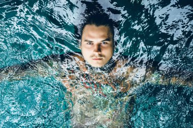 dövmeli adam yağmur havuzunda. yakın çekim, portre, açık havada