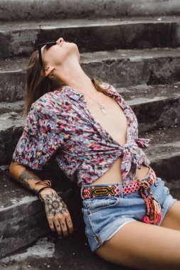 renkli bir gömlek ve belgili tanımlık merdiven üstünde poz güneş gözlüğü giyen güzel kız kot şort uzun bacaklı