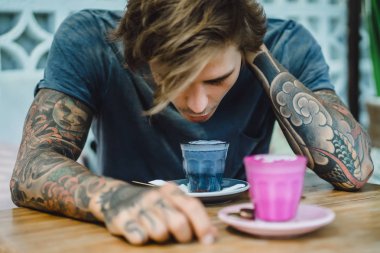 kahve, siyah ve pembe renkli kapuçino. dövmeli bir adam renkli bir kahve bir kafede içecekler..